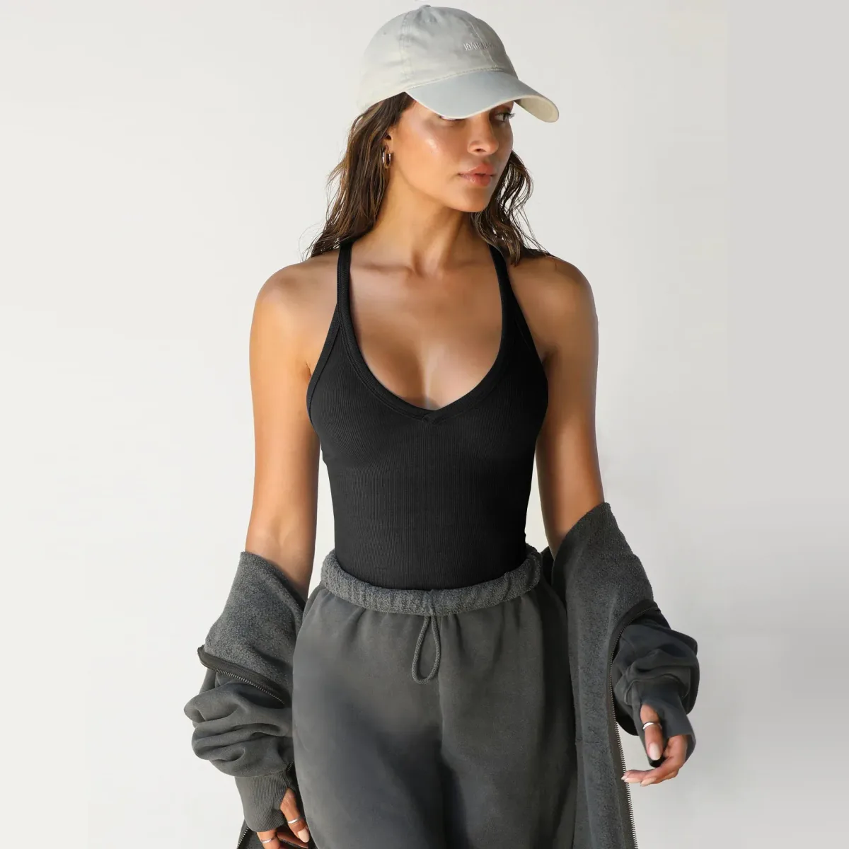 black ribbed V neck tank styled with grey joggers and a cap